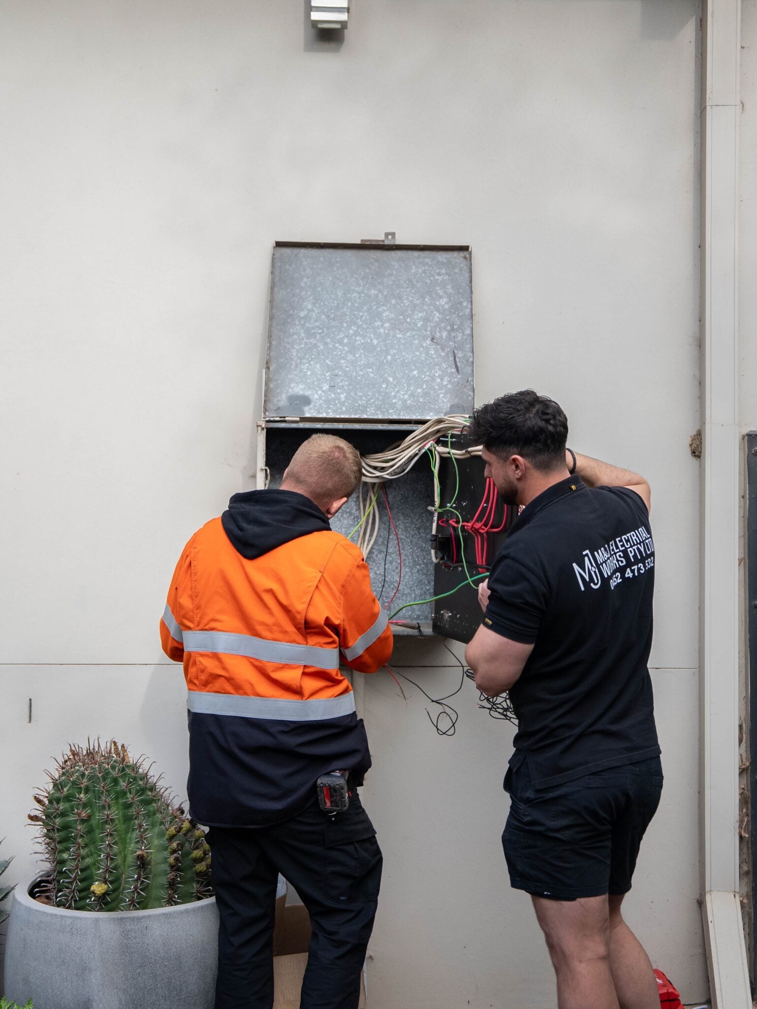 M&J electrician walking a client through a finished switchboard upgrade