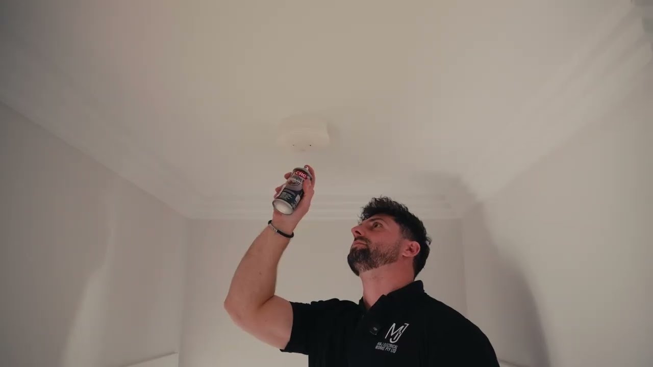 Electrician installing an interconnected photoelectric smoke alarm