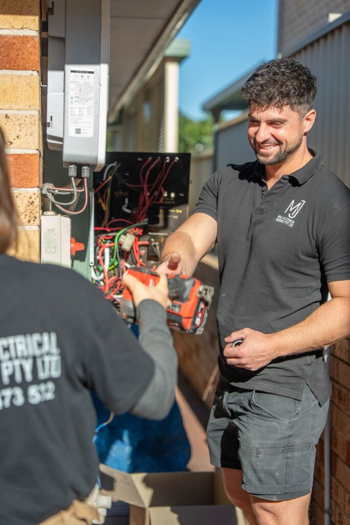 Two electricians passing a drill at the switchboard of a Cecil Hills home
