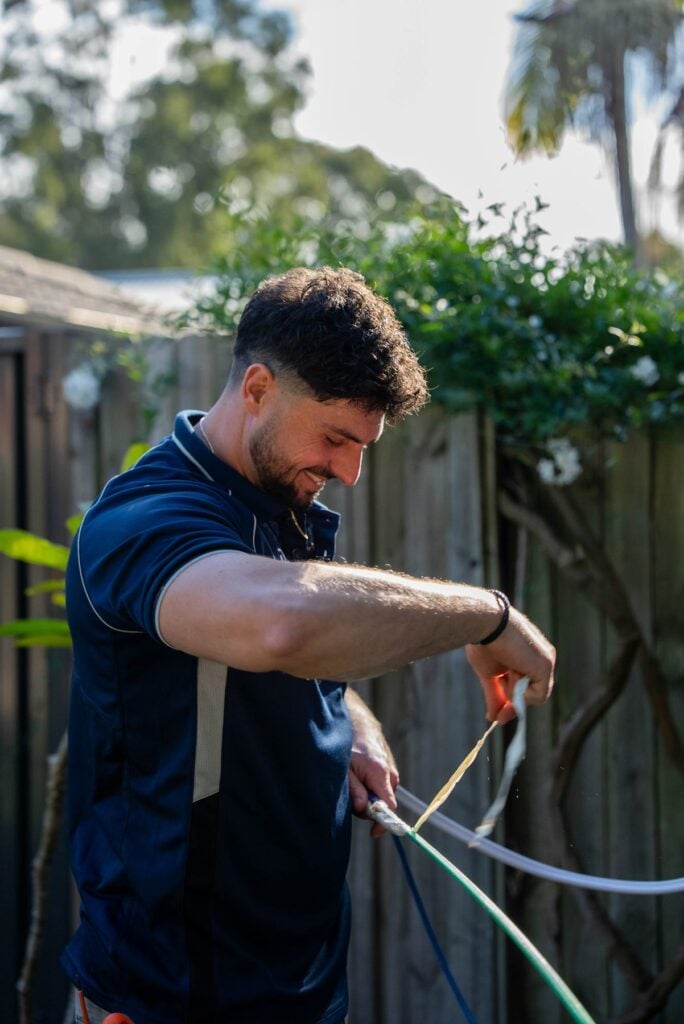 Electrician cutting cable in the backyard of a Narellan Vale home during an EV charger installation