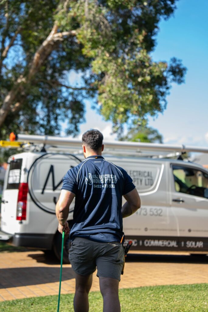 Electrician walking back to the M&J Electrical Works van parked outside a Narellan Vale home