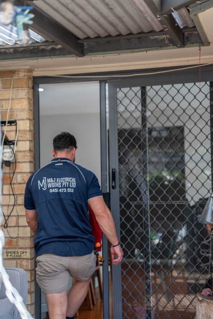 Electrician entering a Narellan Vale home past a shoes-off-please sign at the back door