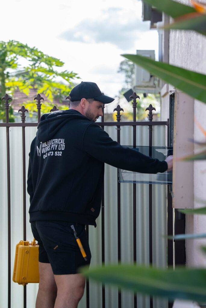 Electrician opening the outdoor meter box on the side of a Leumeah home