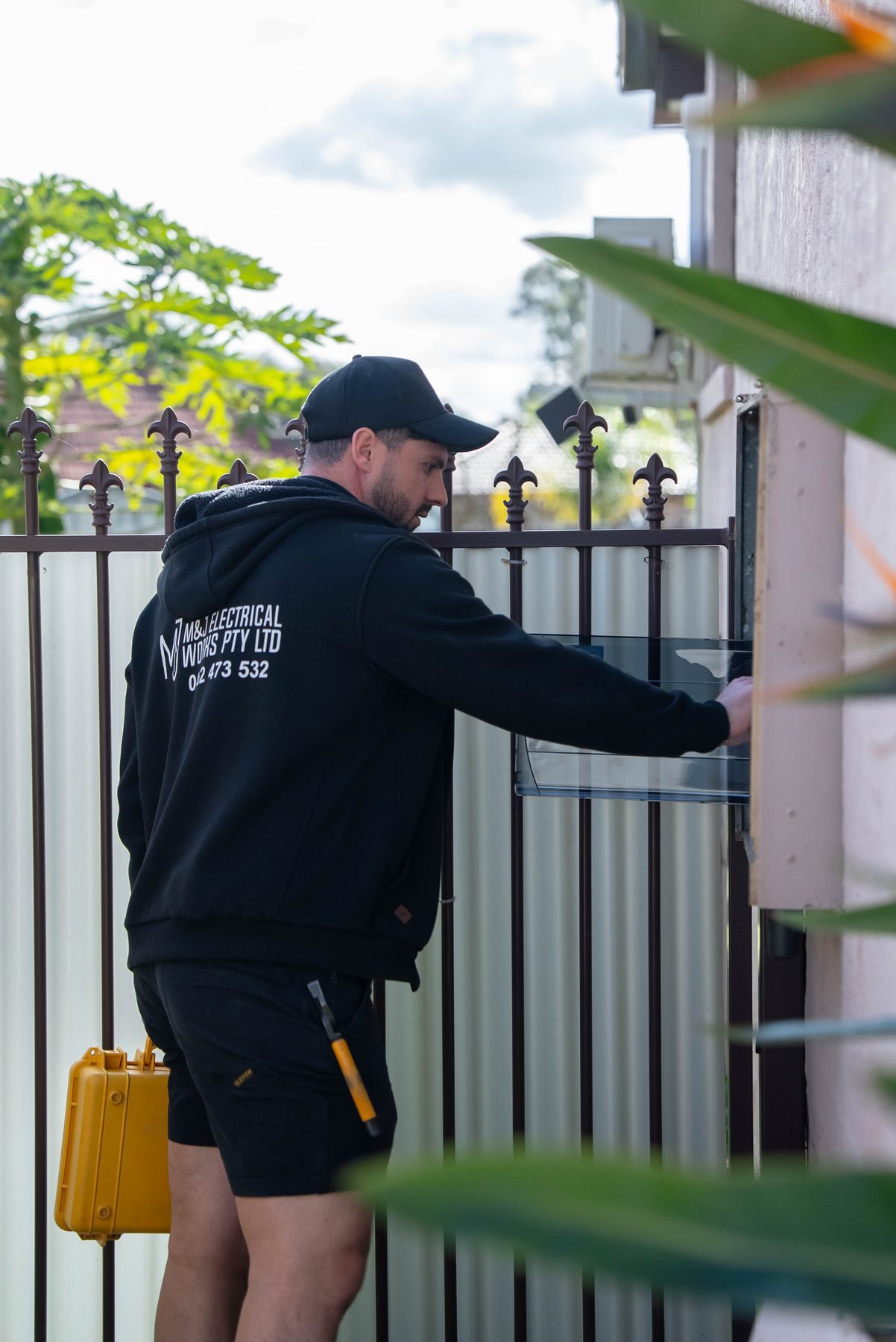 Electrician opening the outdoor meter box on the side of a Leumeah home