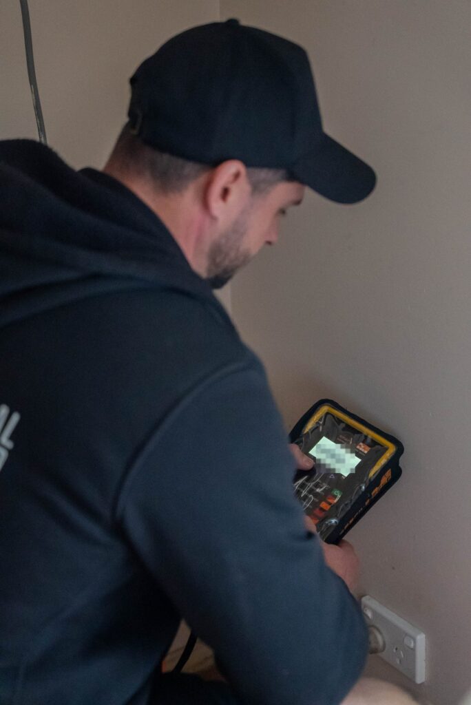 Electrician holding an electrical installation tester while testing circuits at a Leumeah home